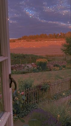 an open window looking out onto a garden at night with stars in the sky above