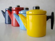 four different colored coffee mugs sitting next to each other on a white counter top