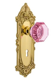 an ornate brass door handle with a pink glass flower on the front and back of it