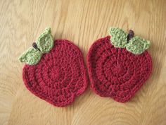 two crocheted apples sitting on top of a wooden table