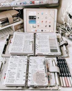 an open book sitting on top of a desk next to a laptop computer and many other items