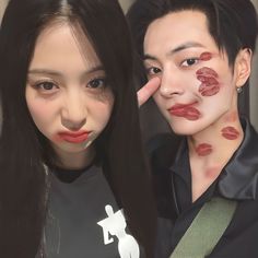 two people with makeup on their faces and one is holding her hand up to the other's face