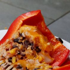 a white plate topped with red bell peppers covered in rice and black bean toppings