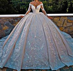 a woman in a wedding dress standing on a stone wall