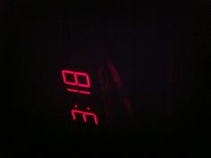 the digital clock is lit up in the dark, with red light on it's face