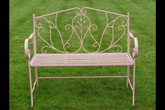 a pink metal bench sitting in the grass