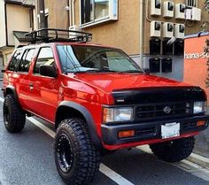 a red pick up truck parked on the side of a road next to a building