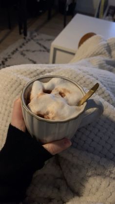 a person is holding a cup of hot chocolate with marshmallows in it