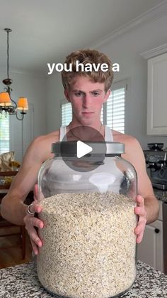 a man holding a large jar filled with oatmeal