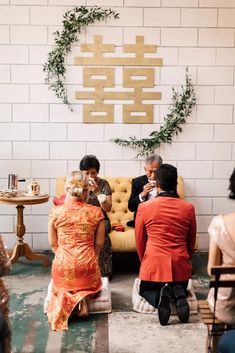 three people sitting on a couch in front of a wall with a circular sign above it