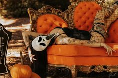 a woman laying on top of an orange couch next to a black and white sign