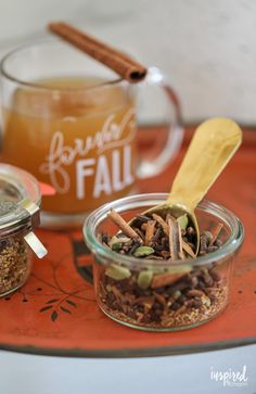 two glass jars filled with spices on top of a red tray next to cinnamon sticks