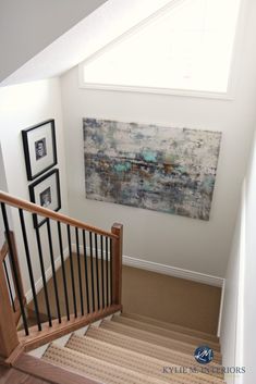 a staircase with pictures on the wall and an art piece hanging over it's railing