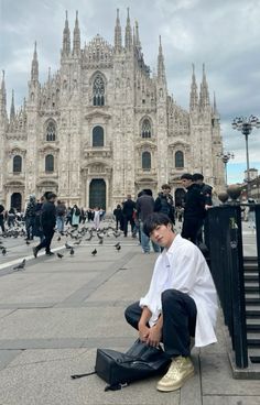 a man sitting on the ground in front of a cathedral