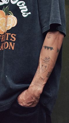 a man with tattoos on his arm holding an orange