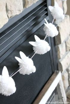 some white paper flowers are hanging from a wire on a fireplace mantel in front of a stone wall