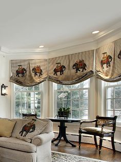 a living room filled with furniture and windows covered in animal themed valances, along with a rug on the floor