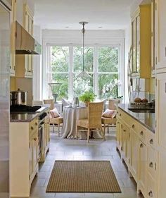 a narrow kitchen with yellow cabinets and white walls, along with an area rug on the floor