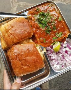 a person holding a tray with some food in it and sauce on the other side