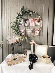 a white table topped with pictures and other items next to a wall mounted photo frame