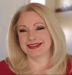 a woman with blonde hair and red dress smiling