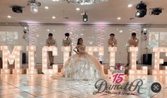 the bride and groom are posing in front of lighted letters that spell out their names