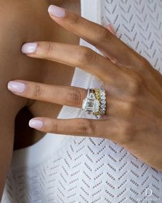 a woman's hand with a ring on her finger and an engagement ring in the other hand