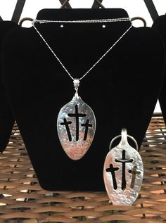 two necklaces with crosses on them sitting on a stand