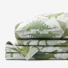 the green and white bedding is made up of sheets with dinosaurs printed on them