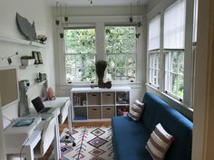 a living room with a blue couch and white table in front of two large windows