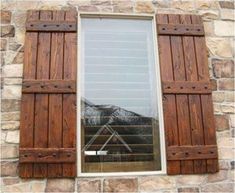 a window with wooden shutters on the side of a stone building