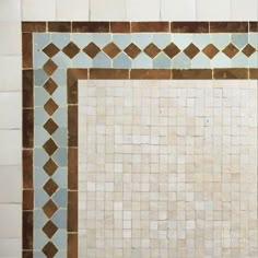 a white tile wall with brown and blue designs on it