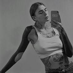 a woman with tattoos holding up her cell phone