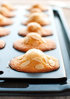 cookies with almonds are lined up on a baking sheet in the oven, ready to be baked