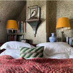 a bed with two lamps on either side of the headboard and bookshelves