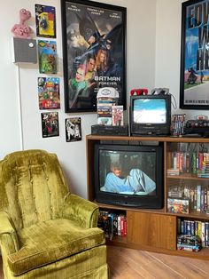 a green chair sitting in front of a tv on top of a wooden cabinet next to a book shelf