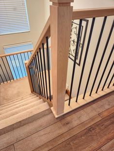 a wooden staircase with black railing and handrails in a new home's entryway