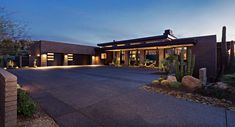 a modern home with cactus and cacti in the front yard at night time