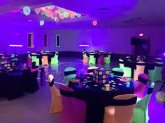 a room filled with lots of tables and chairs covered in purple, green, and blue lights