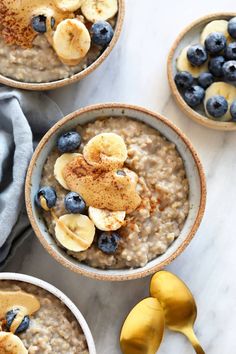 three bowls filled with oatmeal topped with bananas and blueberries