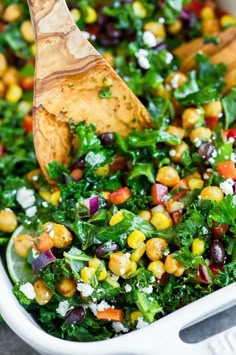 a salad in a white dish with a wooden spoon