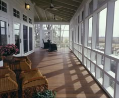 an empty porch with wicker chairs and large windows