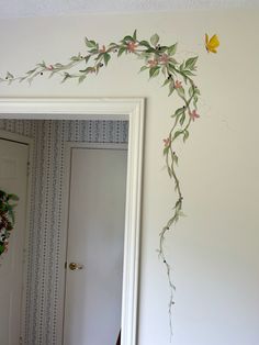 a mirror with flowers painted on it in a room next to a door and wall