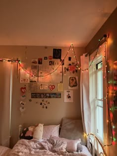 an unmade bed in a bedroom with christmas lights on the wall