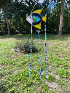 a wind chime with a fish on it in the grass next to some trees