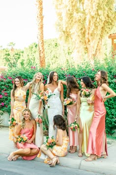 a group of women standing next to each other wearing dresses and holding bouquets in their hands