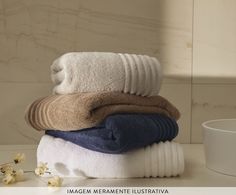 towels stacked on top of each other in front of a cup and vase with flowers