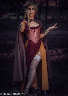 a woman dressed up as a witch in the woods with her hands out to spell