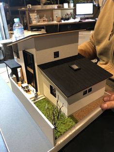 a man holding a model house in his hands