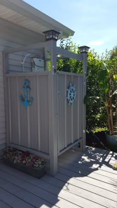 an outdoor shower on a deck with blue decorations and flowers in the planter box